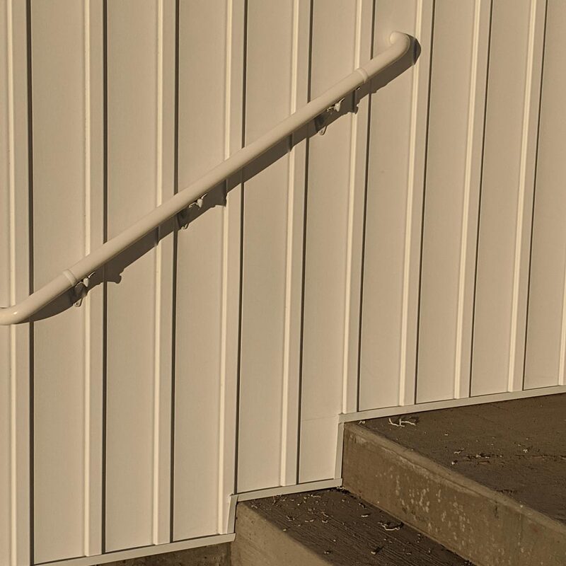 Enhance the safety and modern aesthetic of your exterior or interior entryways with this precise installation by DeckPro LLC. This Minimalist Golden Hour Stairway features durable, raw concrete steps ascending along a clean white vertical panel wall.