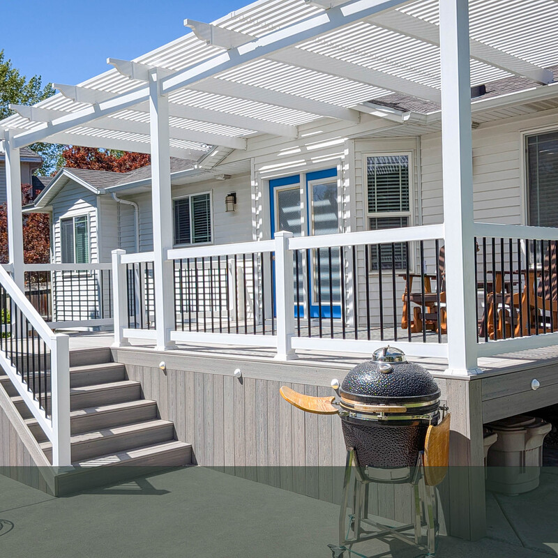 Custom Composite Deck Featuring Built-In Fascia Lighting and Wide Stairs This angled view from the patio highlights the premium finishing touches DeckPro LLC includes in their custom builds. The light grey composite deck features a wide, welcoming staircase leading down to the concrete grilling area. A standout feature of this installation is the integrated LED lighting installed directly into the deck's fascia and stair risers, ensuring maximum safety and a beautiful nighttime ambiance. The matching vertical composite skirting also neatly conceals the under-deck area, keeping the backyard looking pristine.