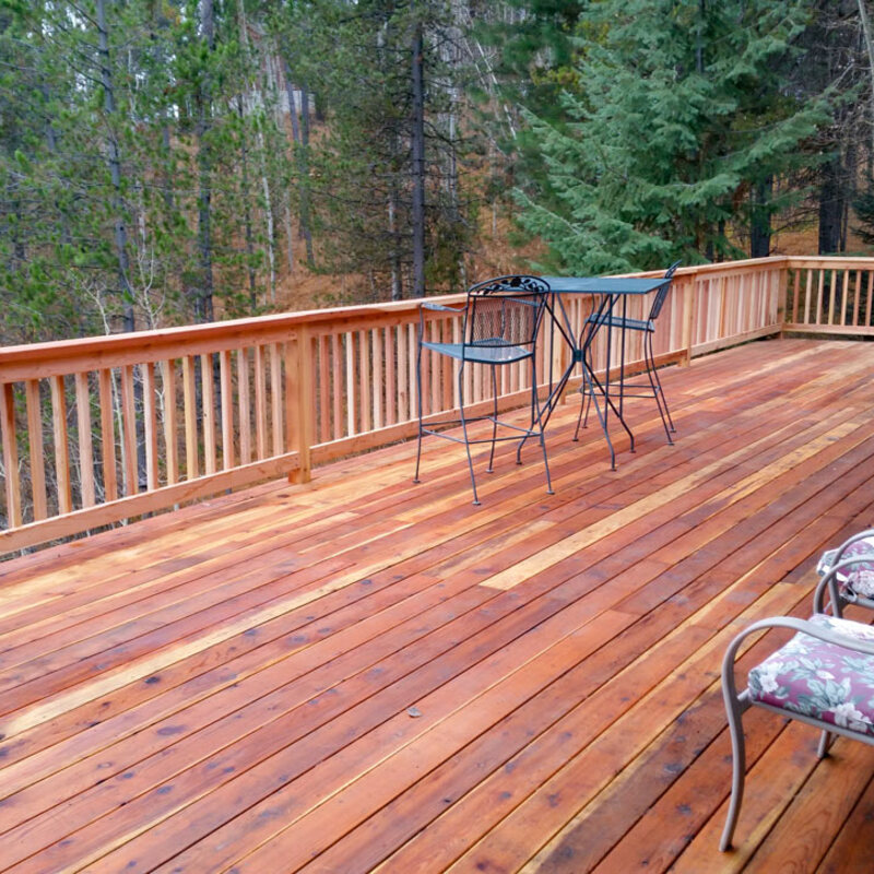 Extend your outdoor living possibilities with this custom deck by DeckPro LLC, which combines rustic elements with modern materials. We installed low-maintenance composite decking in a warm brown tone and paired it with a unique railing system that features natural wood posts and integrated wire mesh infill panels. For the ultimate in functional design, we included extensive built-in L-shaped bench seating, creating a cozy and inviting perimeter perfect for taking in scenic views.