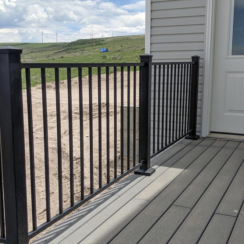 Enhance your home's exterior with The Turbine Vista, a signature custom composite deck by DeckPro LLC. This elevated outdoor living space features premium, durable grey composite decking boards with a low-maintenance, anti-slip surface. The spacious deck is safely enclosed by a safe, code-compliant black metal (aluminum) vertical picket railing system with decorative post caps, offering dynamic all-weather use without compromising views.